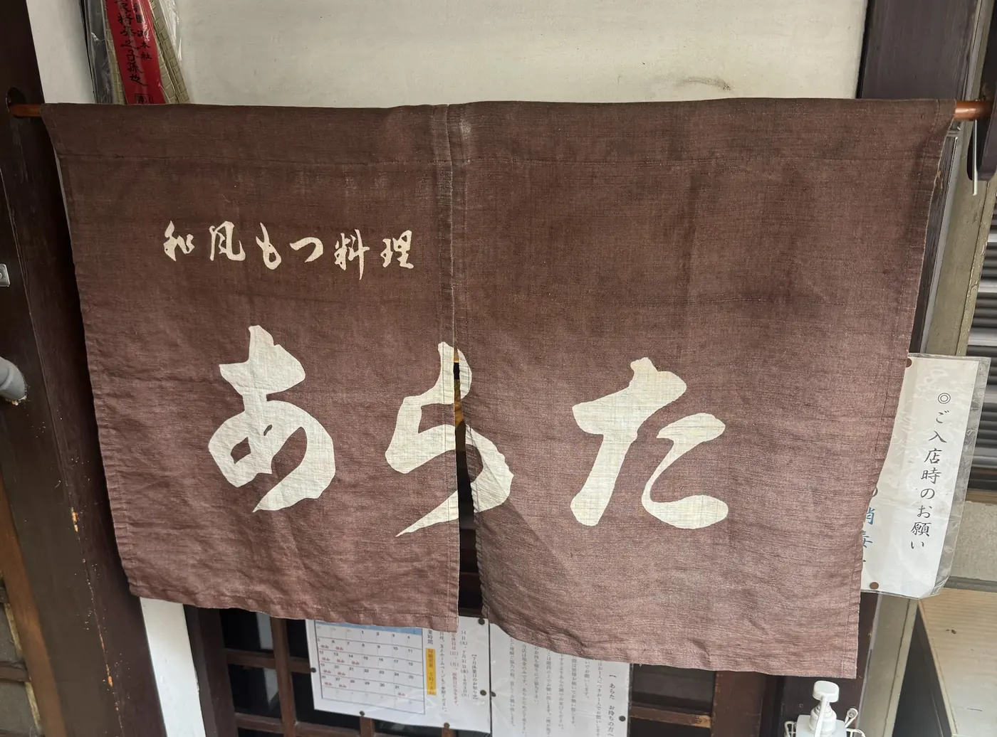 入口にかかる焦げ茶の暖簾「和風もつ料理 あらた」